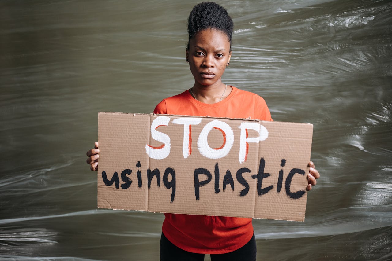 A woman holds a sign reading Stop using plastic for a protest against pollution.